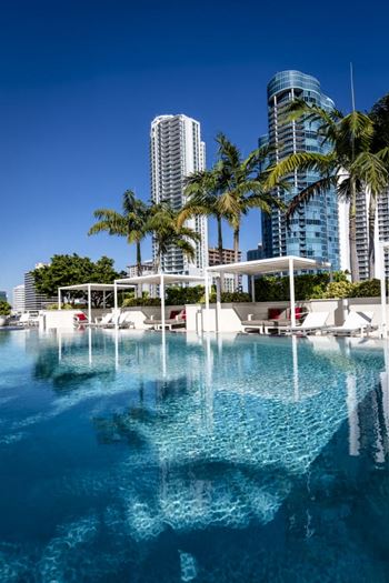 Covered pool deck fully equipped with summer kitchen, communal dining area, fireplace, televisions and lounges